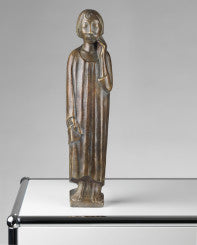 Bronzestatue einer stehenden Figur in einem langen Gewand, die vor einem schlichten Hintergrund einen Gegenstand hält.